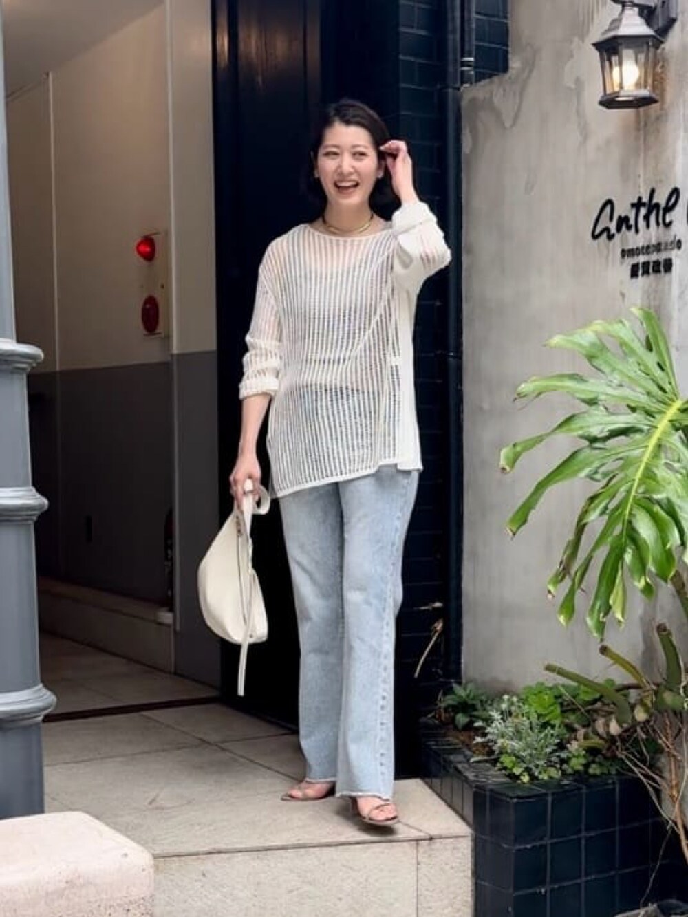 ホワイト系のニット/セーター、ブルー系のデニムパンツ、ホワイト系のボディバッグ/ウエストポーチを着用したレディースの春コーディネートの2枚目の写真