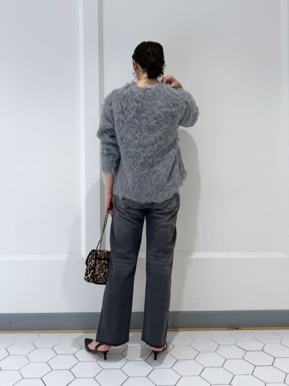 グレー系のニット/セーター、グレー系のデニムパンツ、ベージュ系のショルダーバッグを着用したレディースの秋コーディネートの3枚目の写真