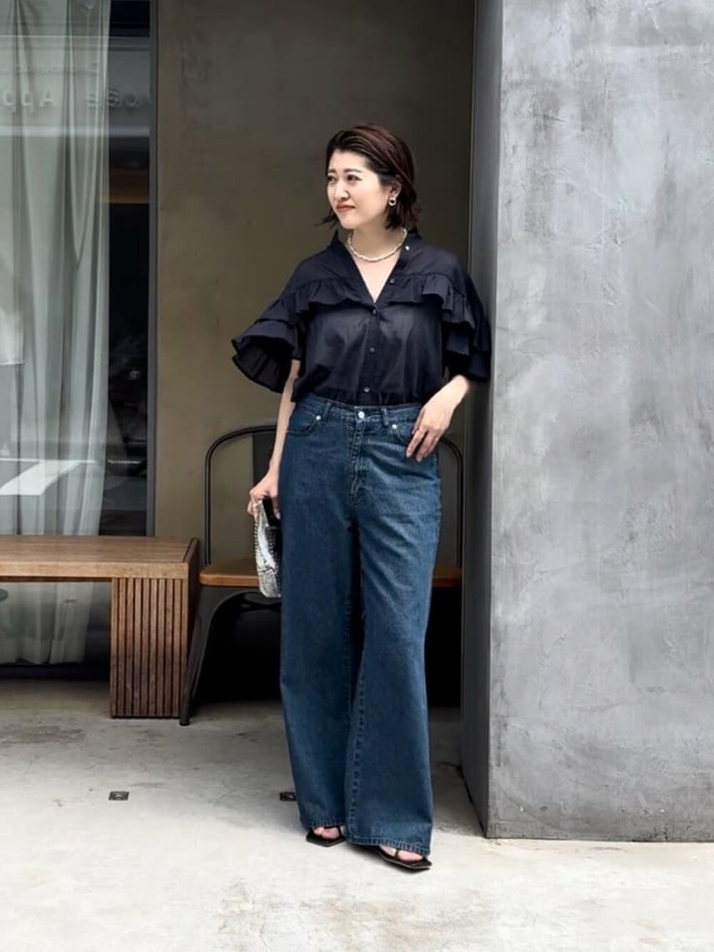 ブラック系のシャツ/ブラウス、ブルー系のデニムパンツを着用したレディースの夏コーディネートの2枚目の写真