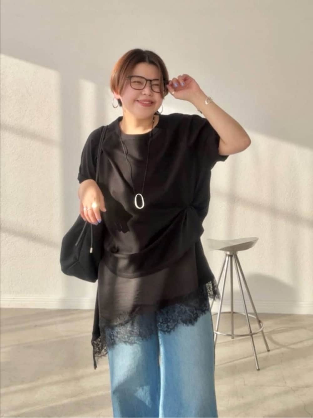 ブラック系のTシャツ/カットソー、ブラック系のキャミソール、ブルー系のデニムパンツを着用したレディースの春コーディネートの3枚目の写真