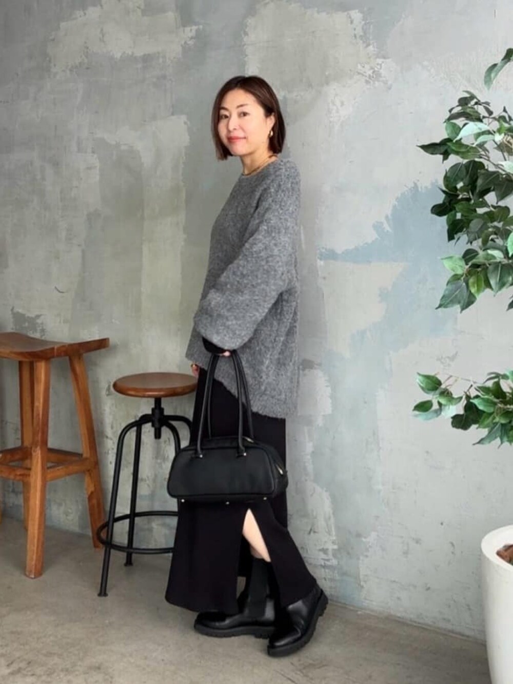 グレー系のニット/セーター、ブラック系のワンピース、ブラック系のショルダーバッグを着用したレディースの秋コーディネートの2枚目の写真
