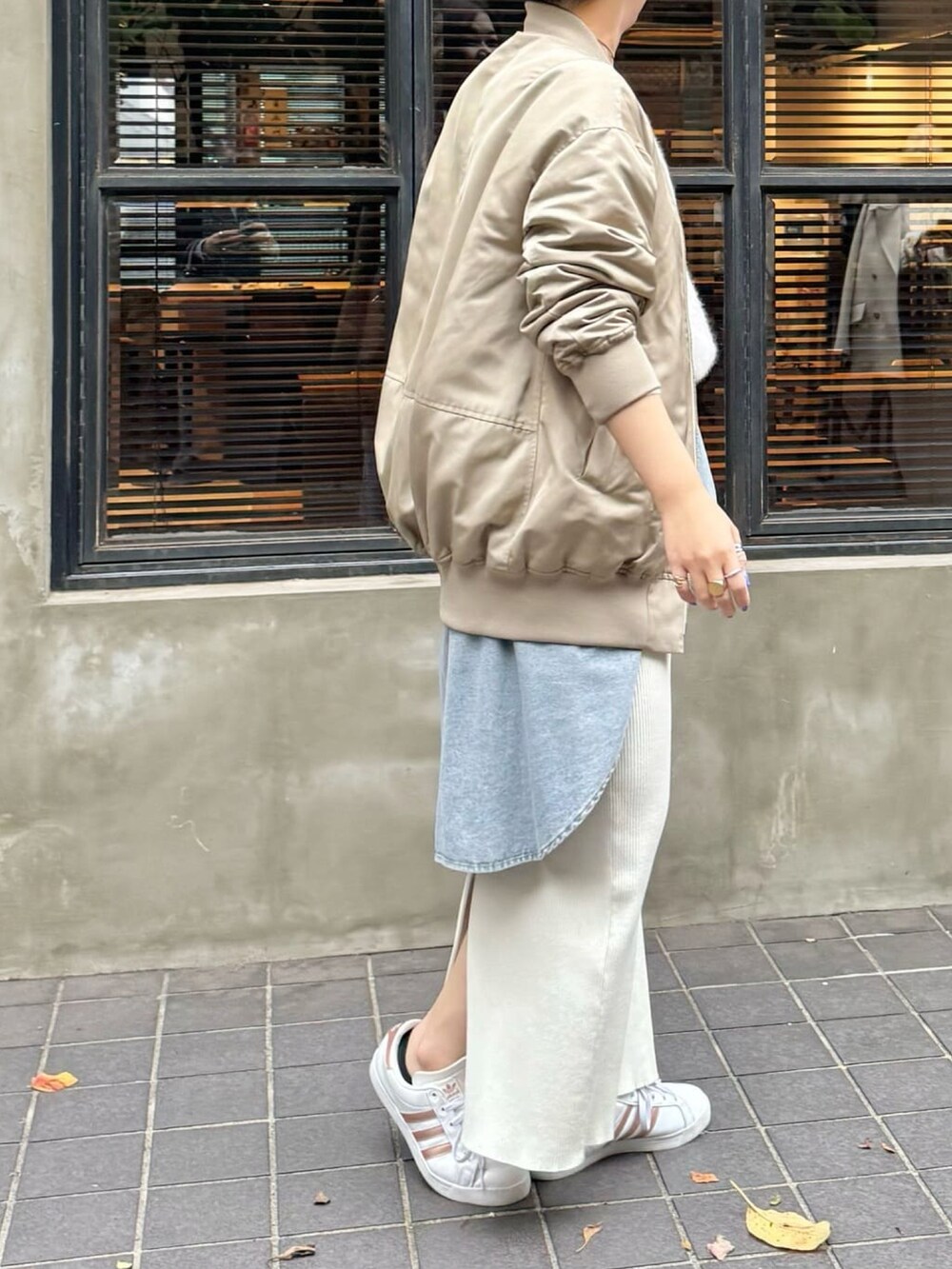 ベージュ系のバッグ、グレー系のニット/セーター、ベージュ系のスカートを着用したレディースの秋コーディネートの2枚目の写真