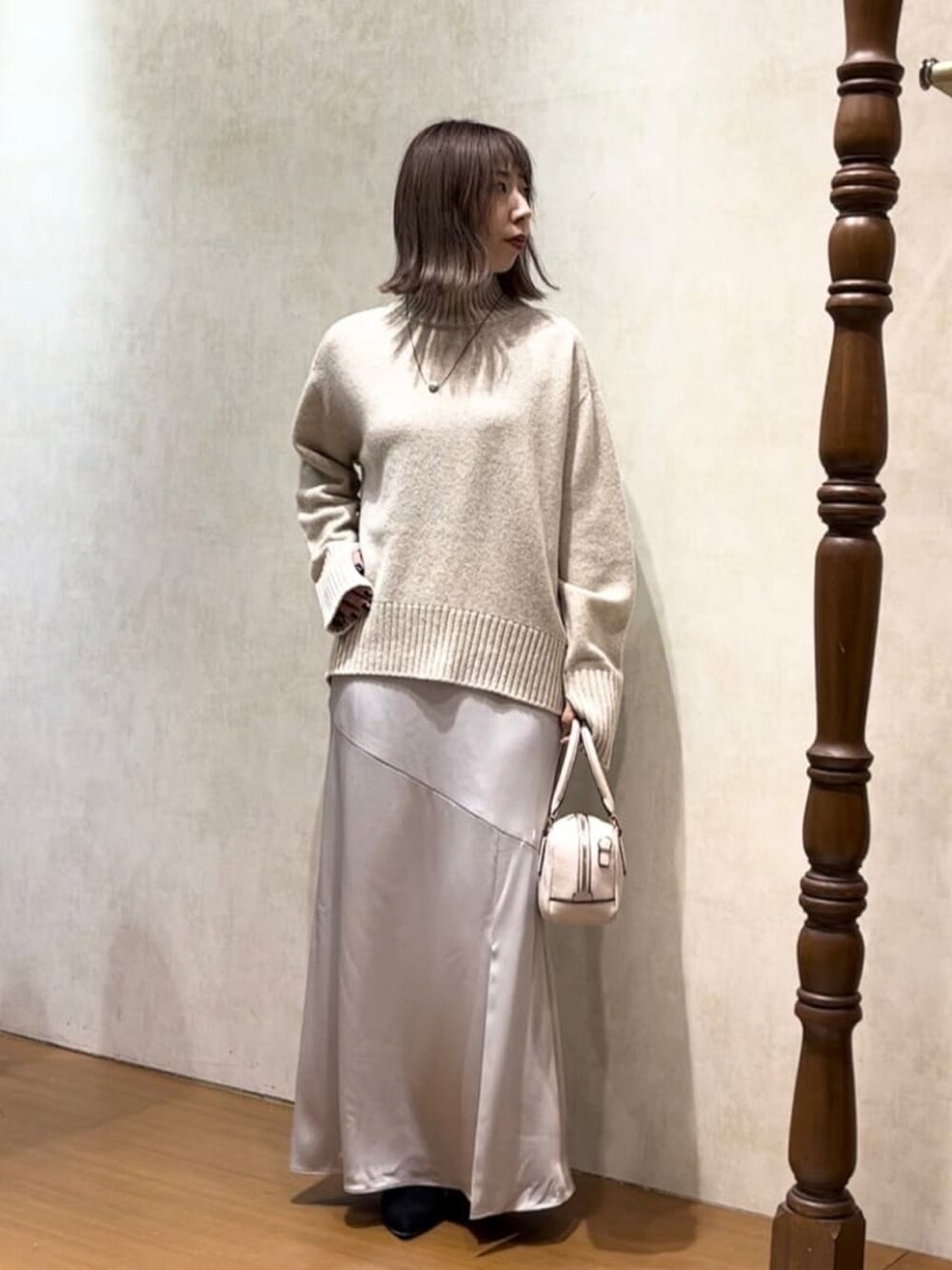 イエロー系のノーカラーコート、グレー系のスカート、ベージュ系のニット/セーターを着用したレディースの秋コーディネートの2枚目の写真
