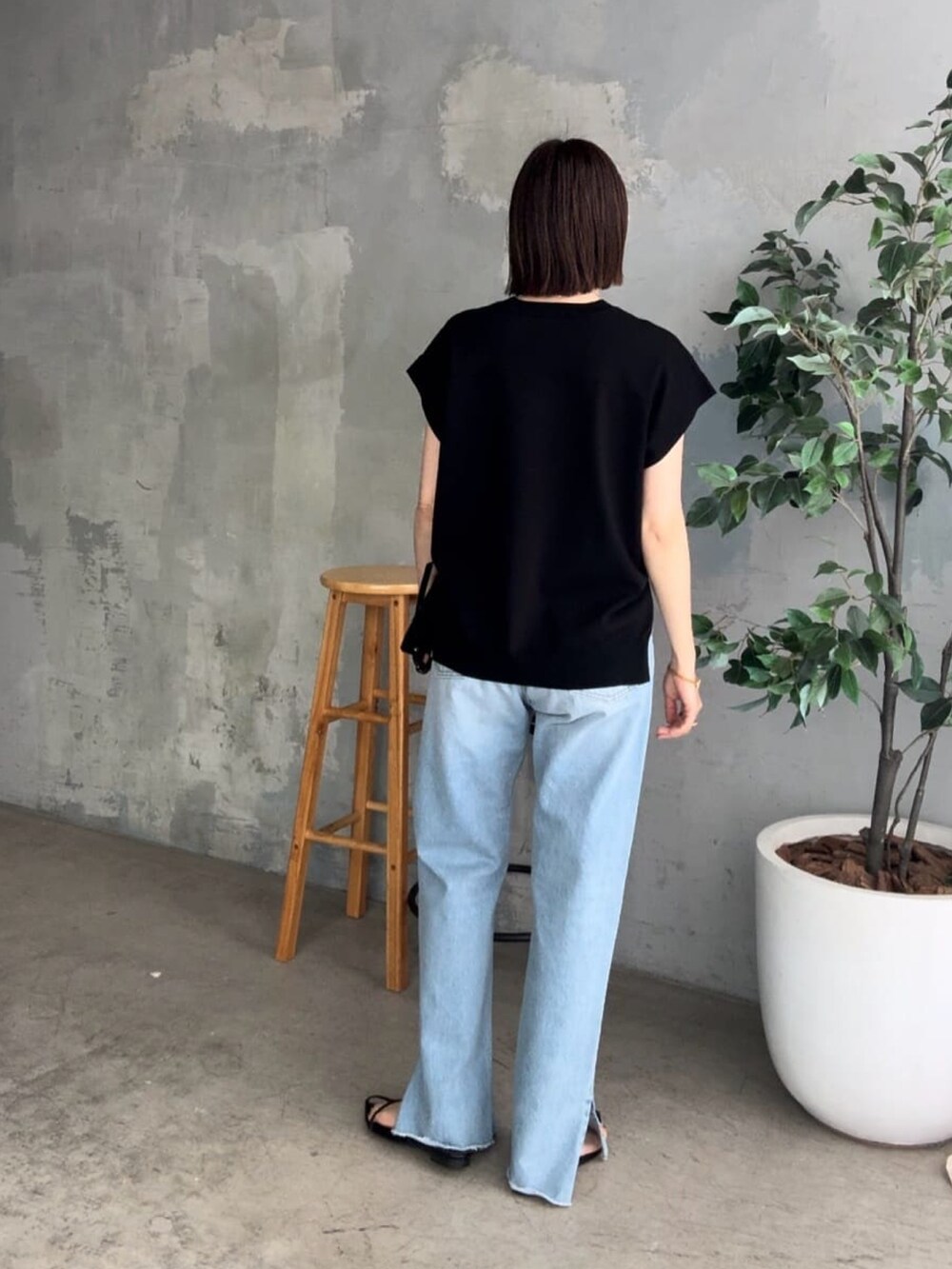 ブラック系のニット/セーター、ブルー系のデニムパンツ、ブラック系のサンダルを着用したレディースの春コーディネートの2枚目の写真