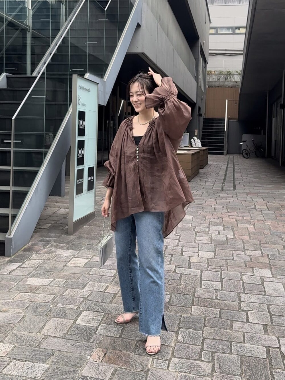 ブルー系のデニムパンツ、ブラック系のサンダル、ベージュ系のシャツ/ブラウスを着用したレディースの春コーディネートの2枚目の写真