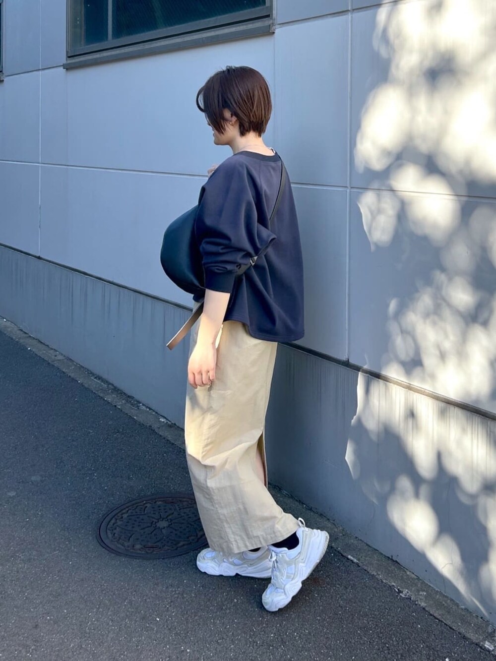 ベージュ系のスカート、ブルー系のスウェット、ブラック系のボディバッグ/ウエストポーチを着用したレディースの春コーディネートの2枚目の写真