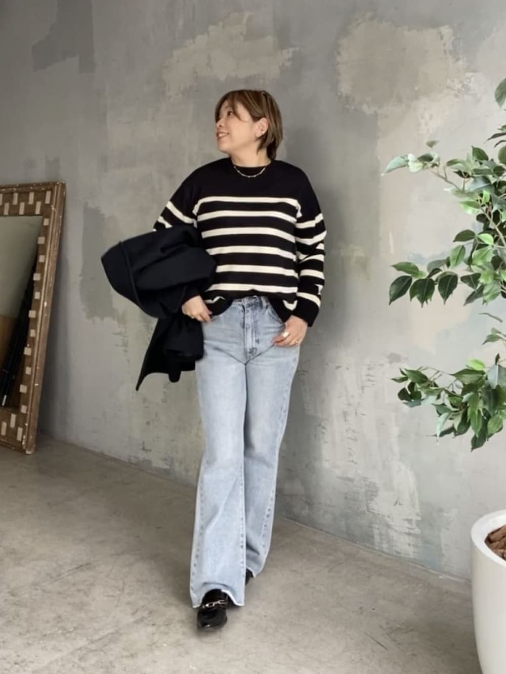 ブラック系のニット/セーター、ブルー系のデニムパンツ、ブラック系のピーコートを着用したレディースの秋コーディネートの2枚目の写真