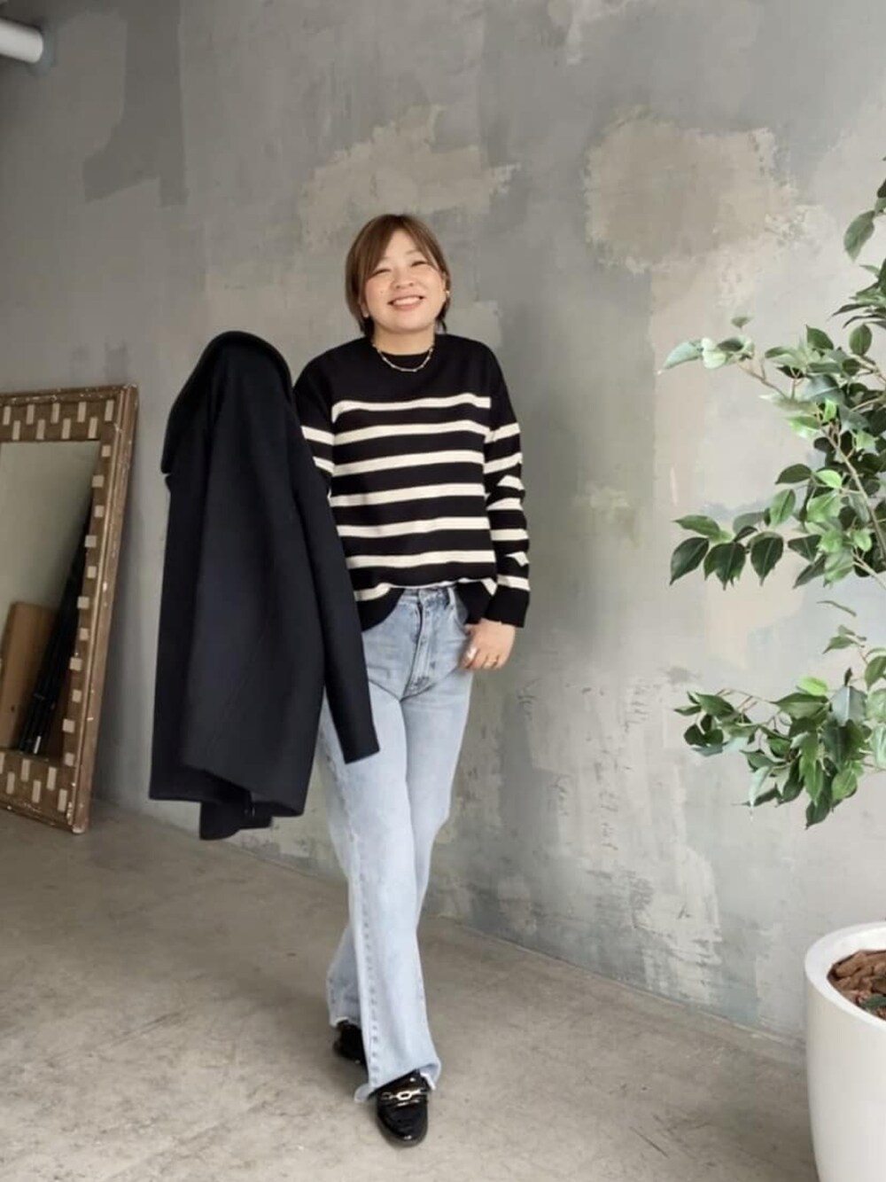 ブラック系のニット/セーター、ブルー系のデニムパンツ、ブラック系のピーコートを着用したレディースの秋コーディネートの3枚目の写真