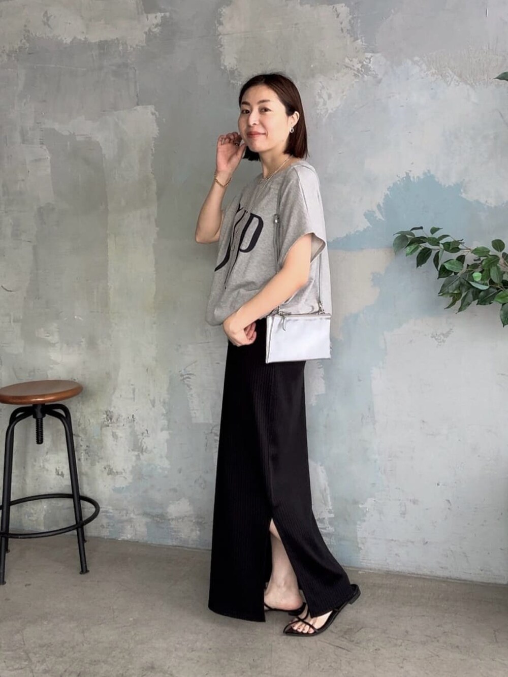 ブラック系のワンピース、ブラック系のサンダル、グレー系のTシャツ/カットソーを着用したレディースの春コーディネートの2枚目の写真