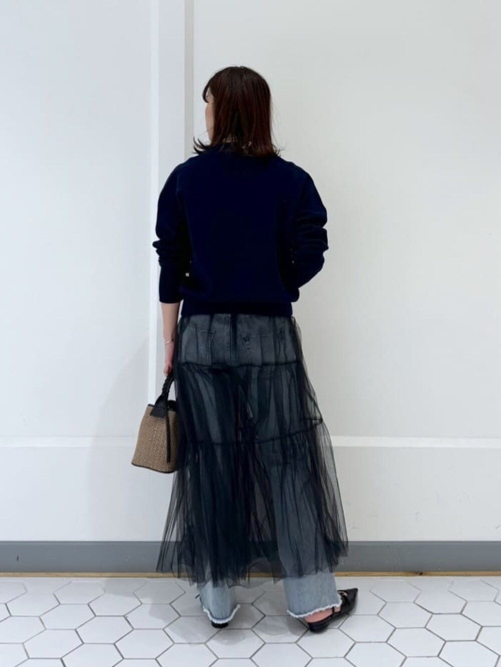 ブルー系のニット/セーター、ブラック系のスカート、ブラック系のハンドバッグを着用したレディースの春コーディネートの4枚目の写真