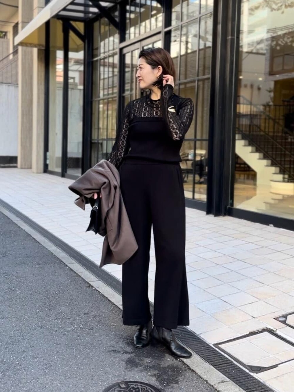 ブラウン系のその他アウター、ブラック系のサロペット/オーバーオール、ブラック系のブーツを着用したレディースの冬コーディネートの3枚目の写真