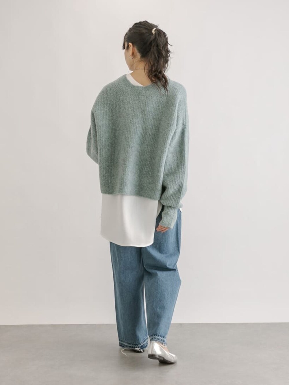 ブルー系のデニムパンツ、イエロー系のボストンバッグ、グリーン系のニット/セーターを着用したレディースの冬コーディネートの3枚目の写真