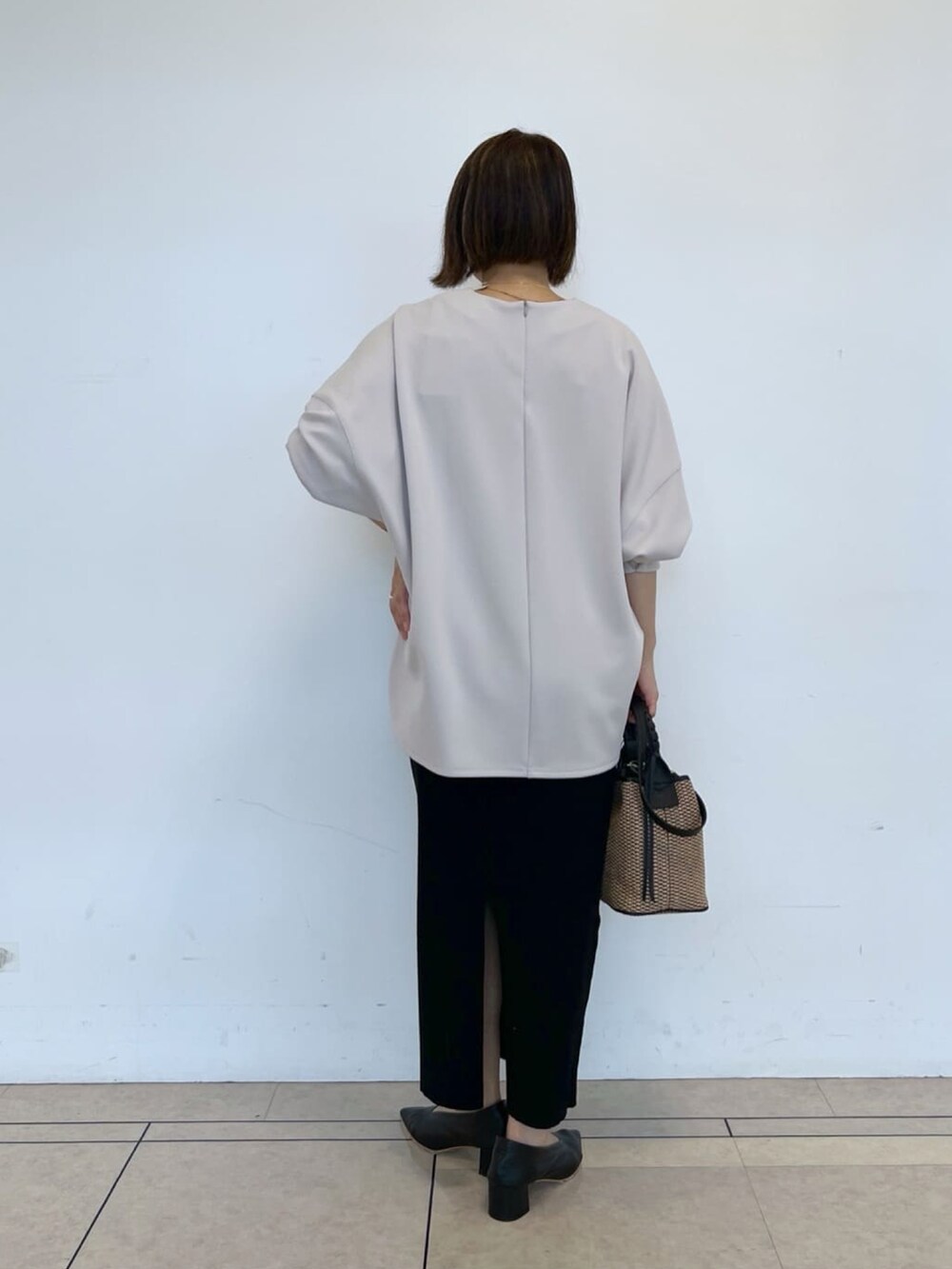 グレー系のTシャツ/カットソー、ブラック系のスカート、ブラック系のハンドバッグを着用したレディースの春コーディネートの3枚目の写真