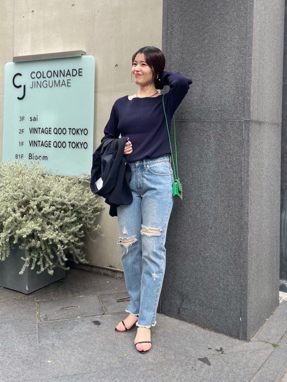 ブルー系のテーラードジャケット、ブルー系のニット/セーター、グリーン系のショルダーバッグを着用したレディースの春コーディネートの3枚目の写真