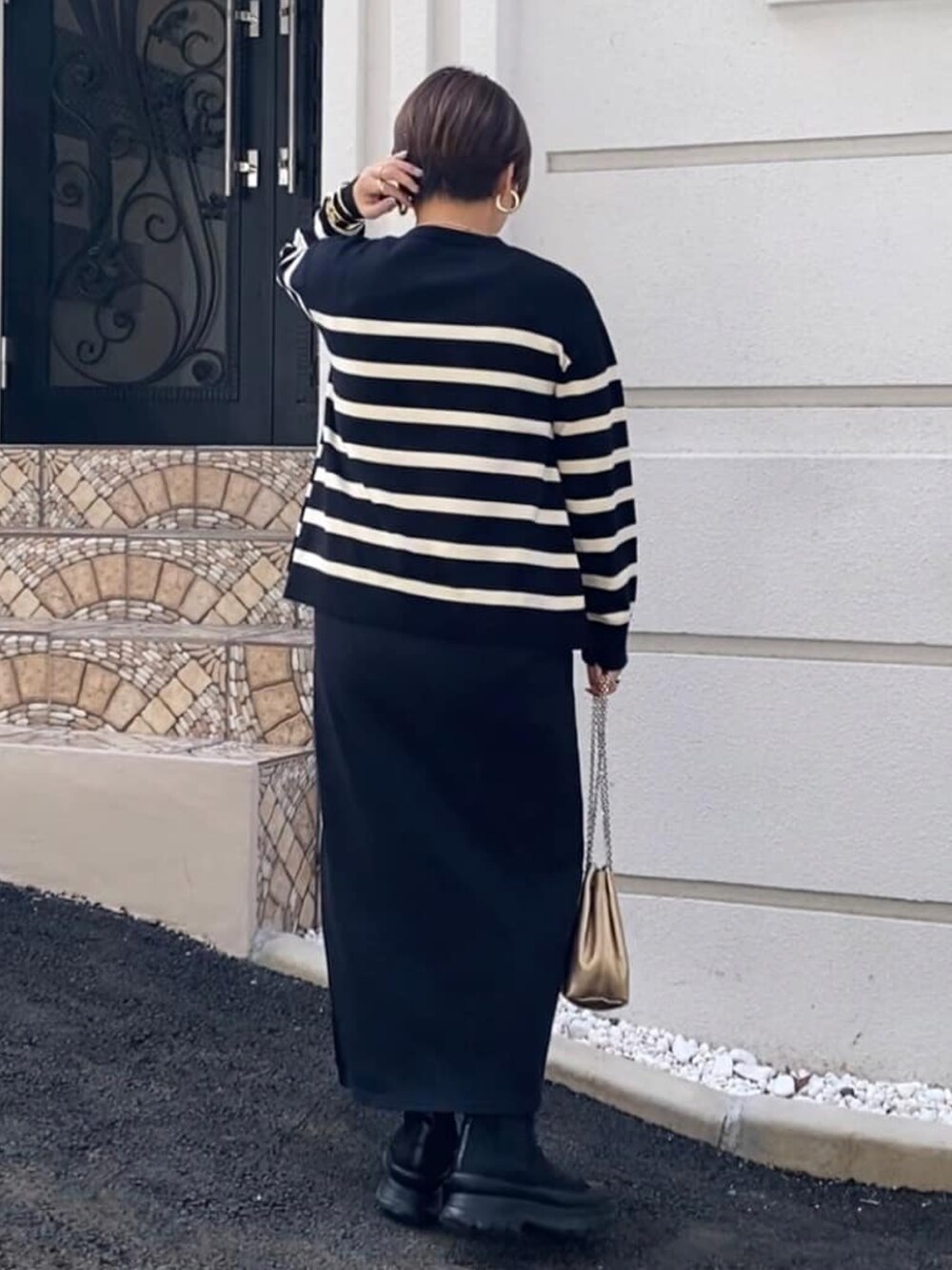 ブラック系のニット/セーター、ブラック系のスカート、ブラック系のブーツを着用したレディースの秋コーディネートの2枚目の写真