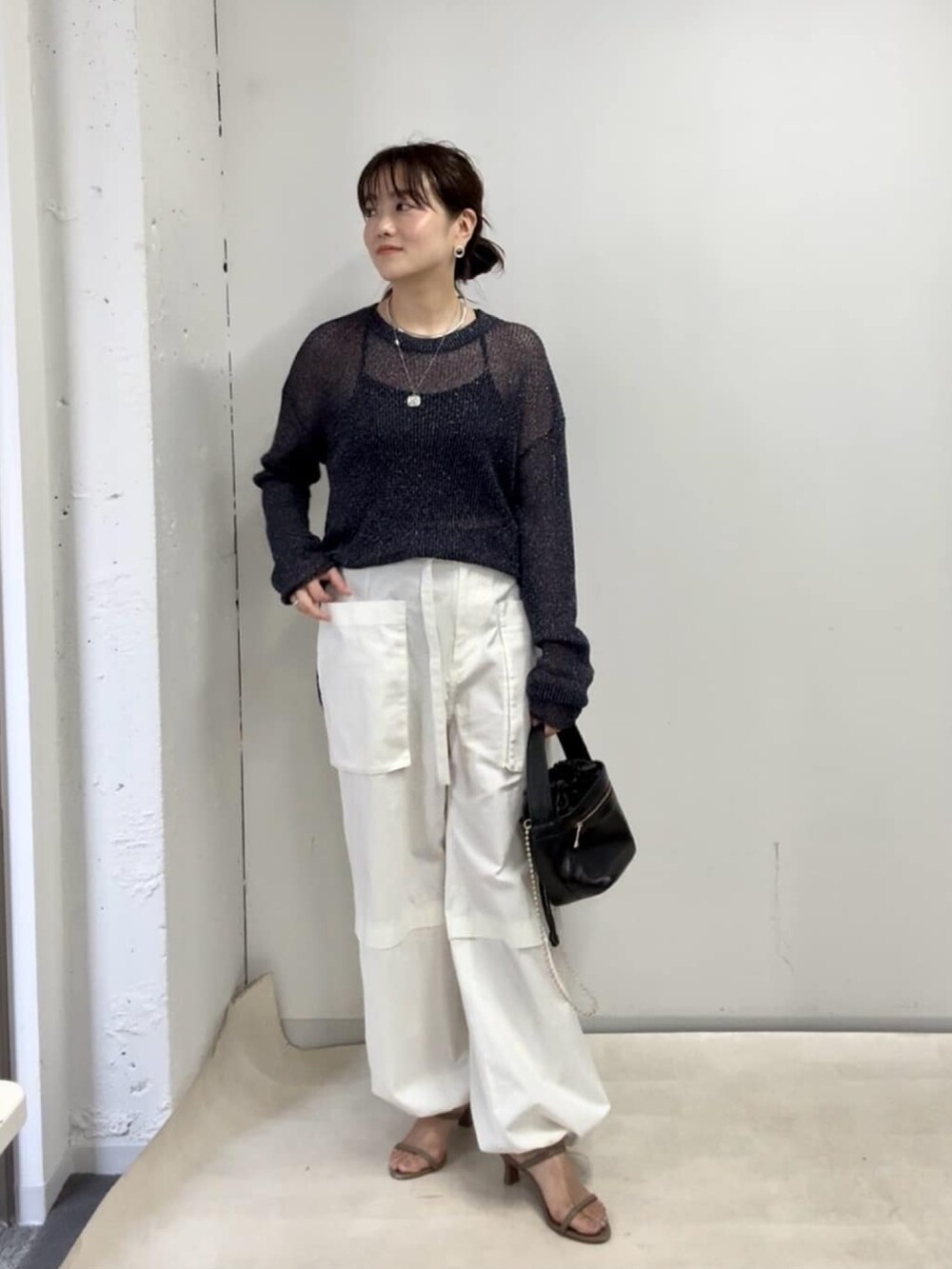 ブルー系のニット/セーター、ホワイト系のカーゴパンツ、ブラック系のハンドバッグを着用したレディースの夏コーディネートの2枚目の写真