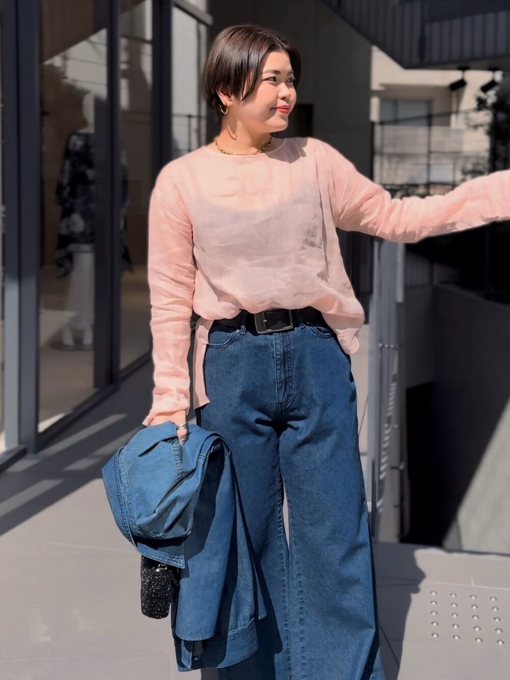 ピンク系のシャツ/ブラウス、ブラック系のショルダーバッグ、ブルー系のデニムパンツを着用したレディースの春コーディネートの3枚目の写真