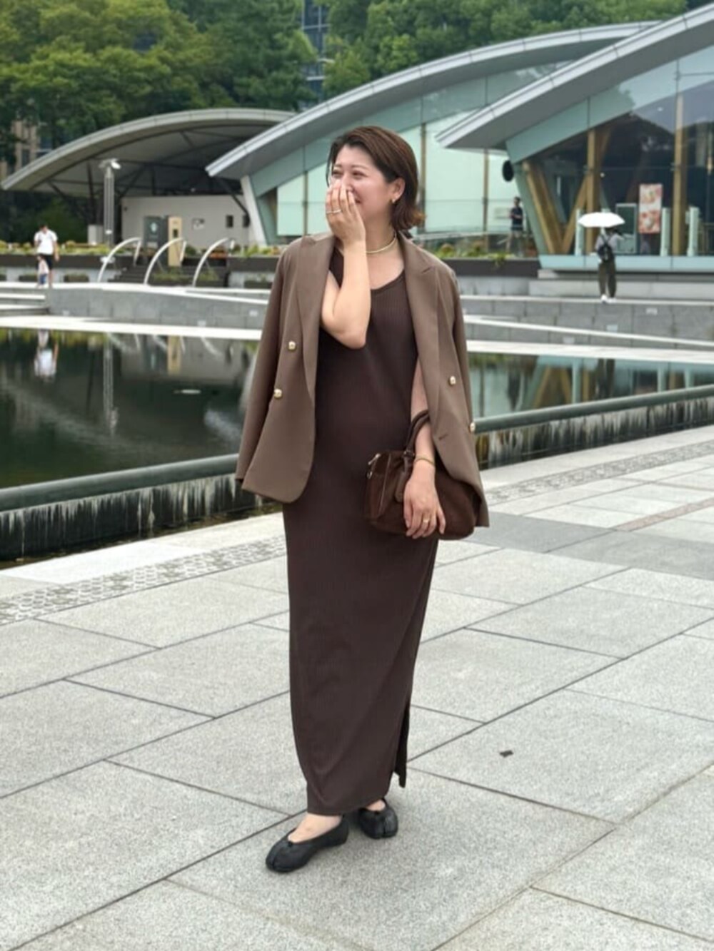 ブラウン系のテーラードジャケット、ブラウン系のワンピース、ゴールド系のチョーカーを着用したレディースの秋コーディネートの2枚目の写真