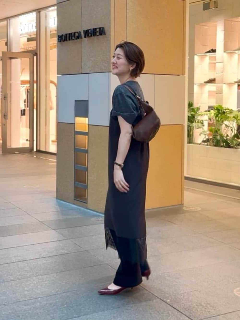 ブラウン系のショルダーバッグ、グレー系のTシャツ/カットソー、レッド系のパンプスを着用したレディースの夏コーディネートの2枚目の写真