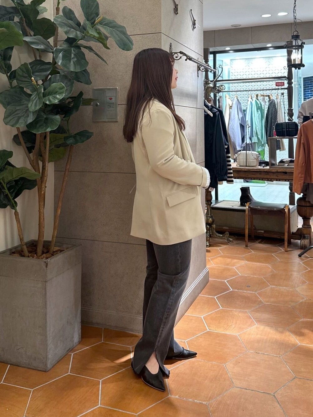 グレー系のデニムパンツ、ベージュ系のテーラードジャケット、ブラック系のパンプスを着用したレディースの冬コーディネートの2枚目の写真