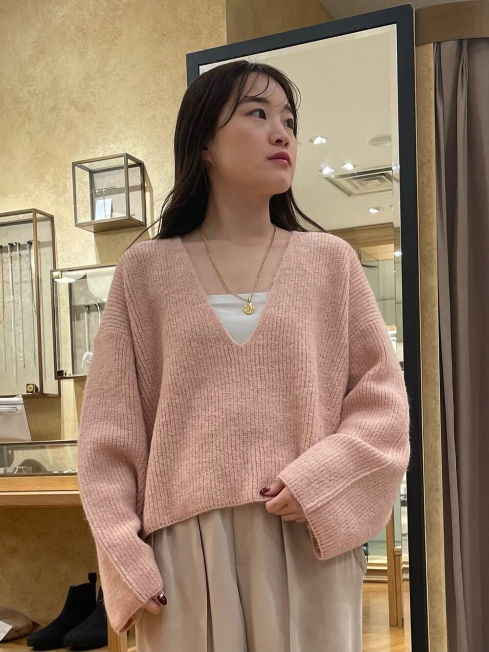 ピンク系のニット/セーター、グレー系のスラックスを着用したレディースの冬コーディネートの3枚目の写真