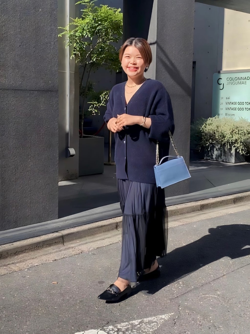 ブルー系のカーディガン/ボレロ、ブラック系のスカート、ブルー系のハンドバッグを着用したレディースの冬コーディネートの2枚目の写真