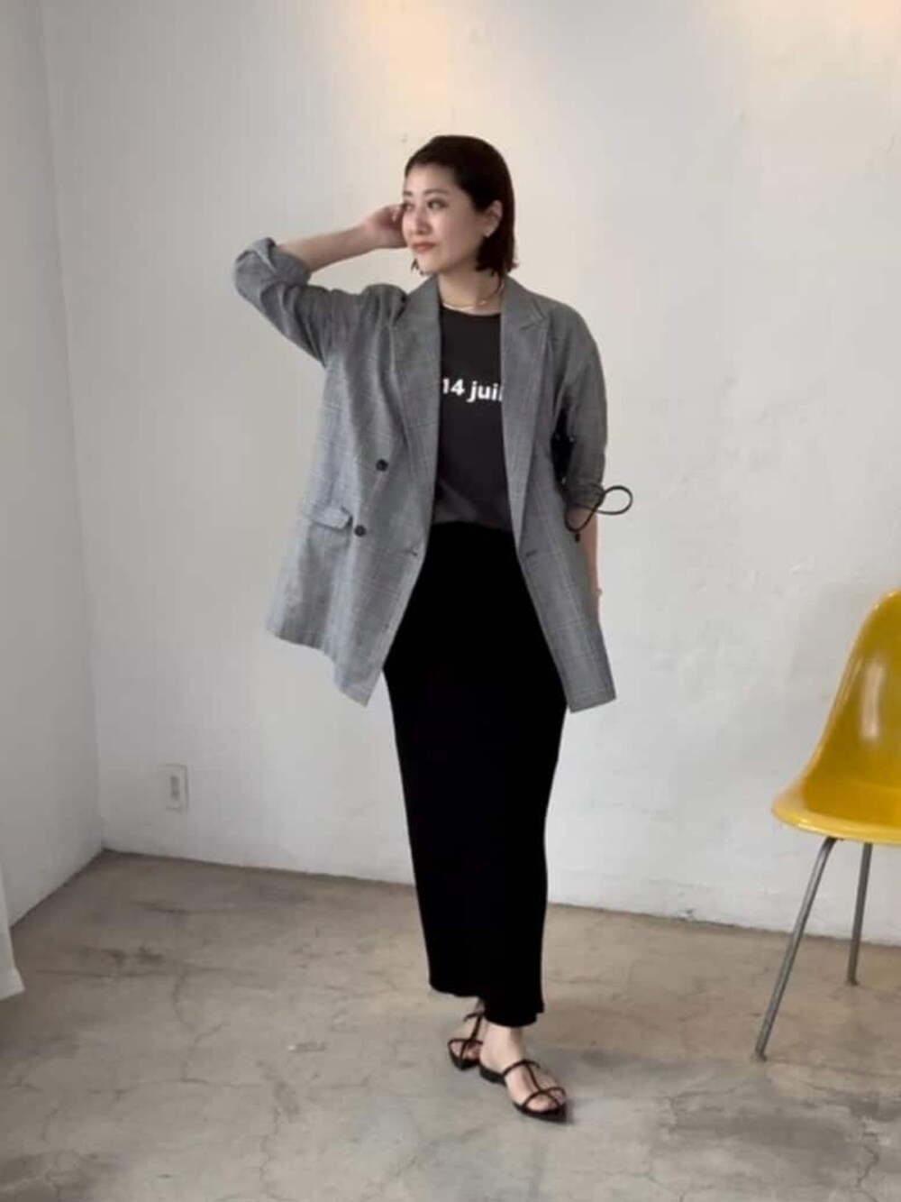 グレー系のテーラードジャケット、ブラック系のスカート、ブラック系のサンダルを着用したレディースの春コーディネートの2枚目の写真