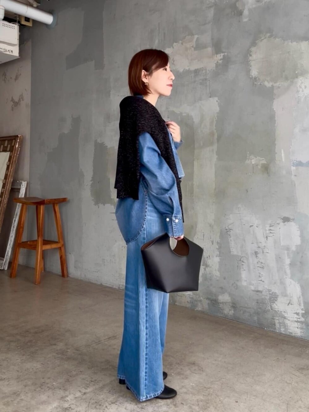 ブラック系のニット/セーター、ブルー系のシャツ/ブラウス、ブルー系のデニムパンツを着用したレディースの秋コーディネートの3枚目の写真