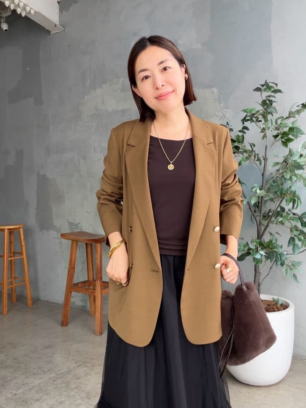 ブラウン系のテーラードジャケット、ブラウン系のTシャツ/カットソー、ブラック系のスカートを着用したレディースの秋コーディネートの4枚目の写真