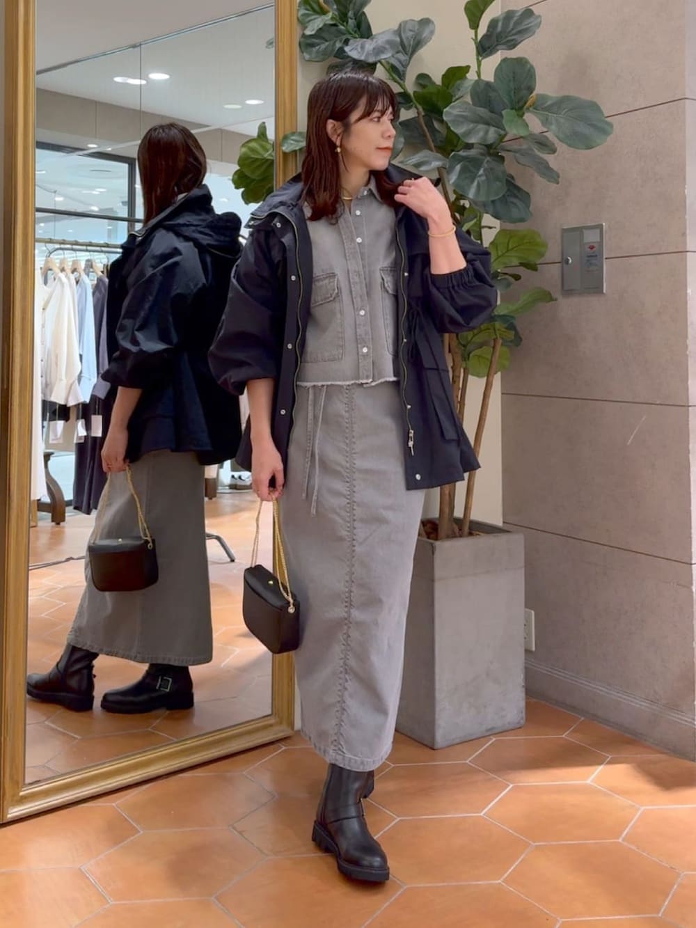 グレー系のシャツ/ブラウス、グレー系のデニムスカート、ブラック系のマウンテンパーカーを着用したレディースの冬コーディネートの2枚目の写真