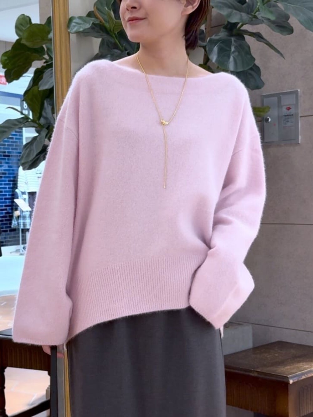 ピンク系のニット/セーター、グレー系のスカート、ブラック系のブーツを着用したレディースの秋コーディネートの4枚目の写真