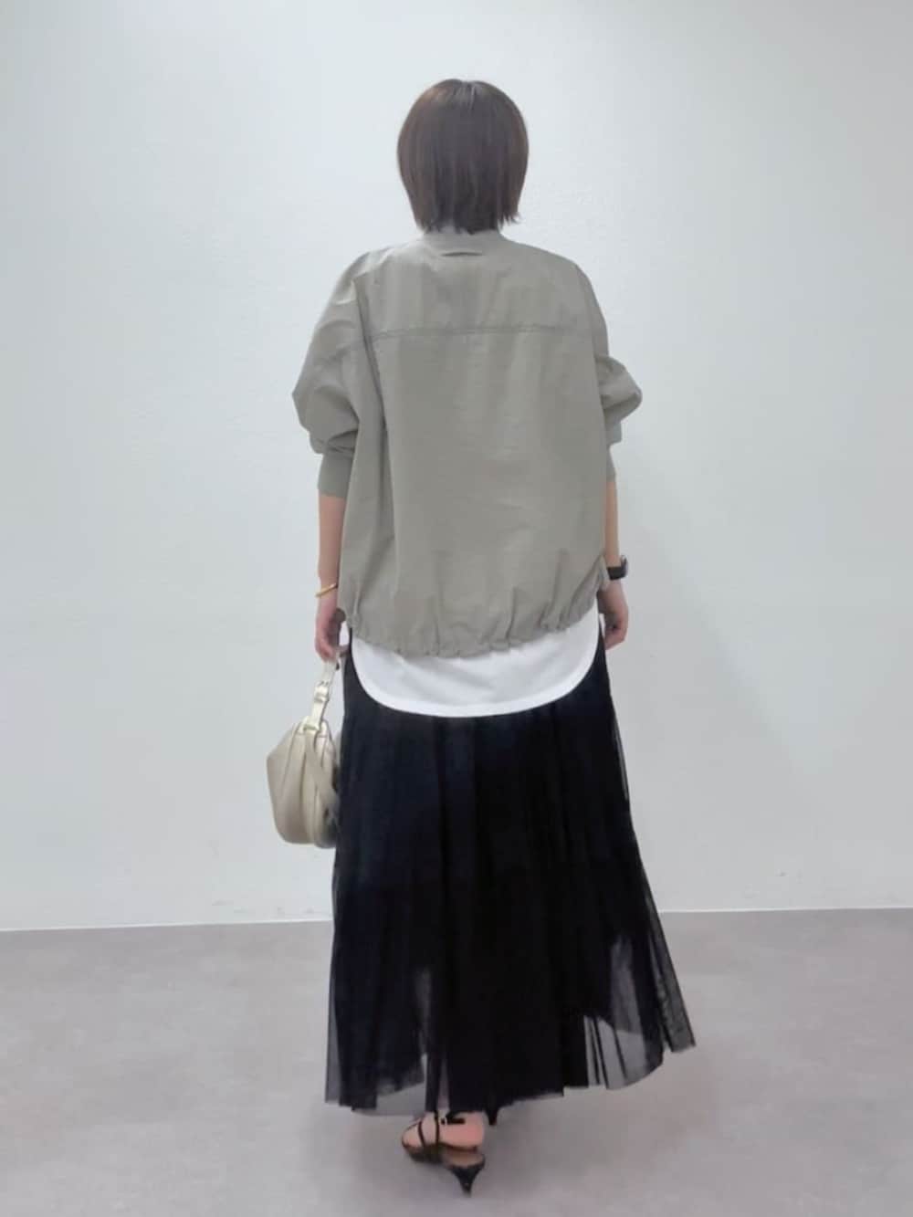 ブラック系のサンダル、ゴールド系のショルダーバッグ、グリーン系のブルゾンを着用したレディースの春コーディネートの5枚目の写真