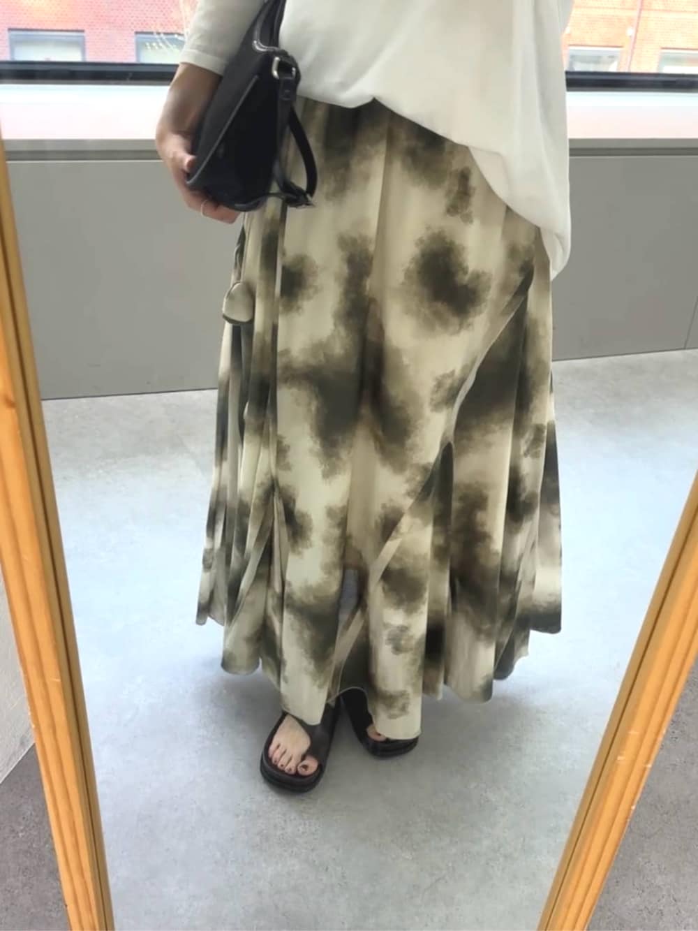 ブラック系のハンドバッグ、ベージュ系のスカート、ブラウン系のサンダルを着用したレディースの春コーディネートの3枚目の写真