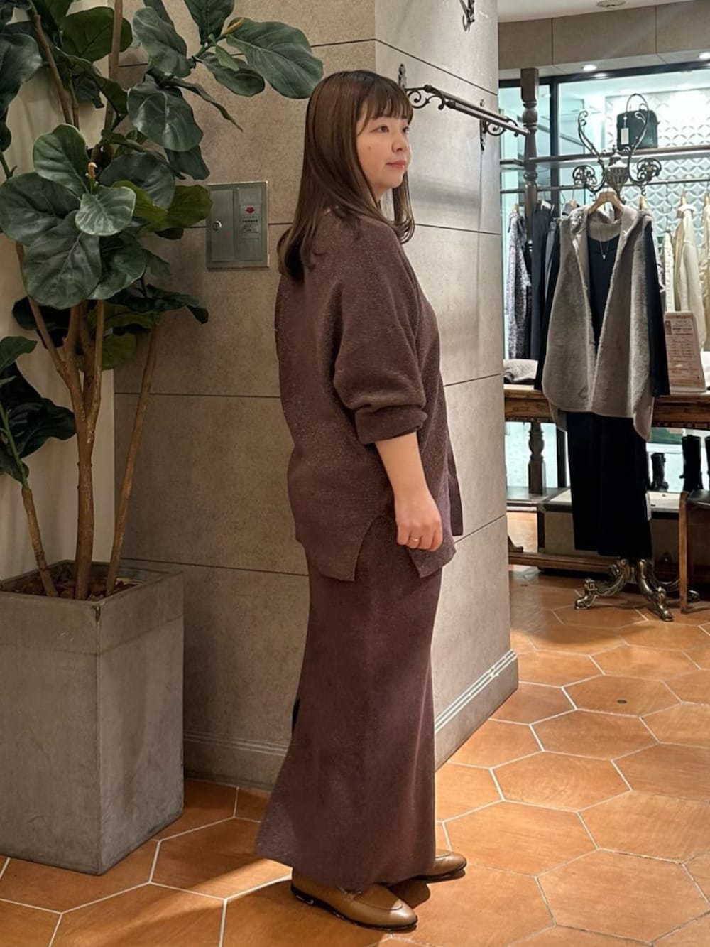 ブラウン系のニット/セーター、ブラウン系のスカート、イエロー系のローファーを着用したレディースの冬コーディネートの2枚目の写真