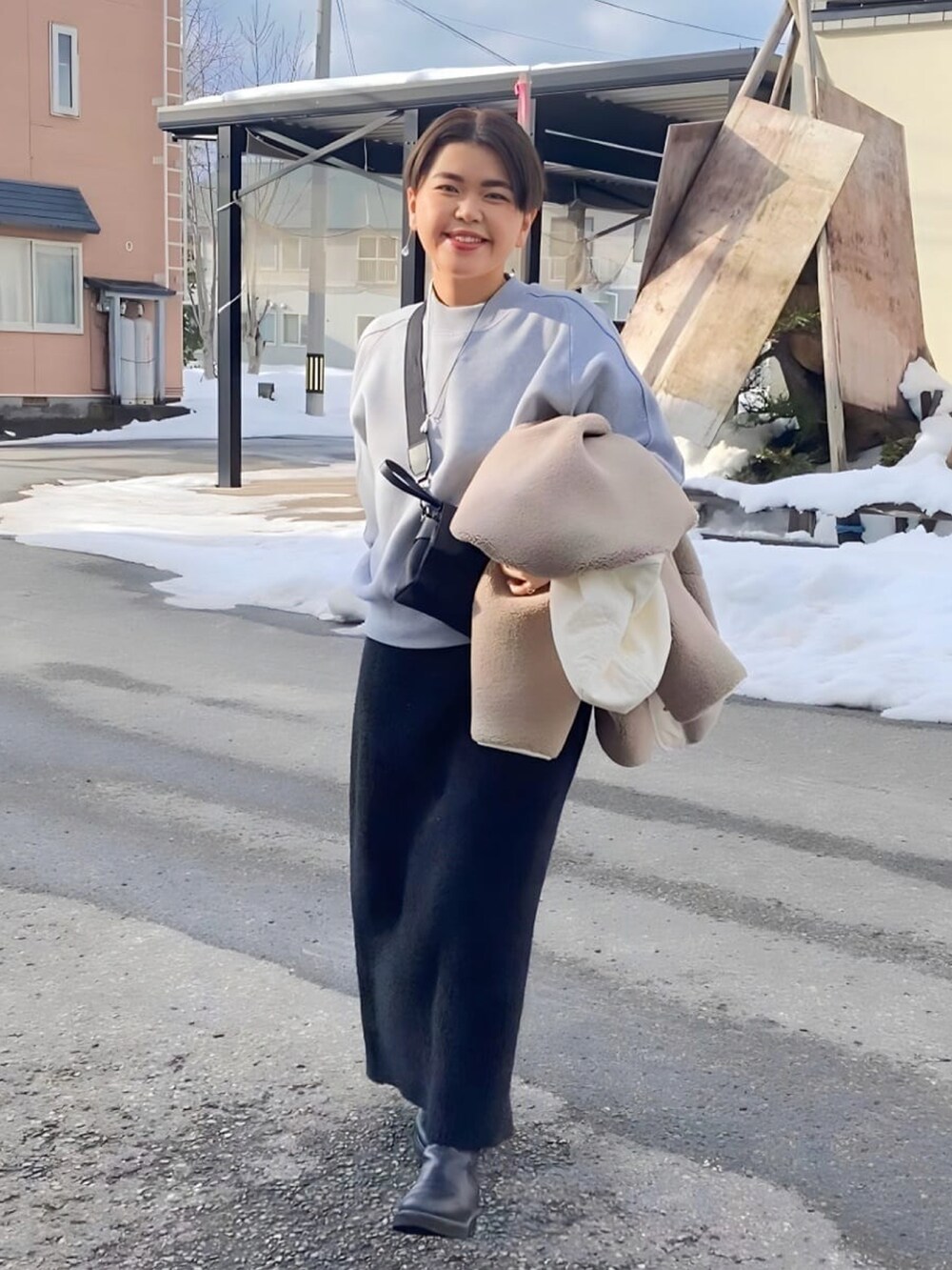 ブラック系のブーツ、グレー系のニット/セーター、ブラック系のスカートを着用したレディースの冬コーディネートの2枚目の写真