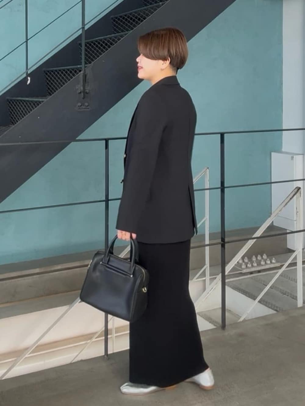 ブラック系のテーラードジャケット、ブラック系のボストンバッグ、ブラック系のワンピースを着用したレディースの冬コーディネートの3枚目の写真