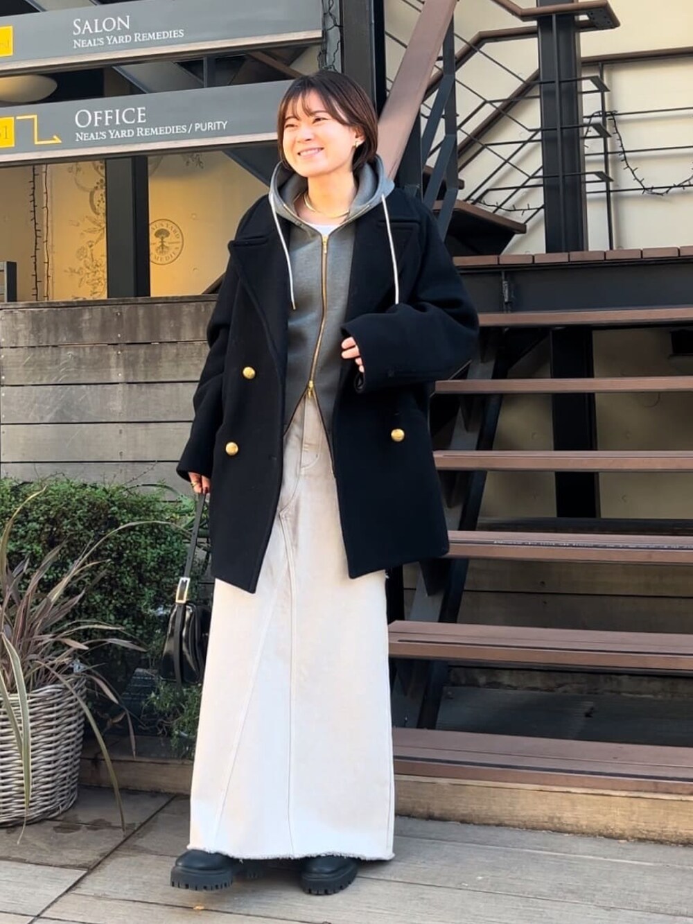 グレー系のパーカー、グレー系のデニムスカート、ブラック系のショルダーバッグを着用したレディースの冬コーディネートの4枚目の写真