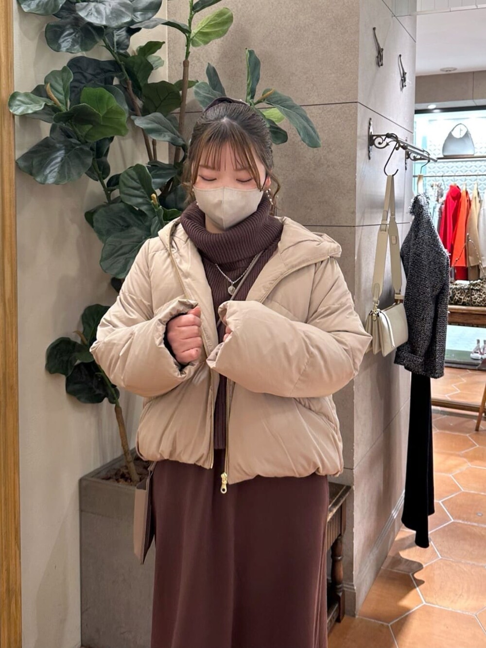 ブラウン系のワンピース、ブラック系のブーツ、ブラック系のダウンジャケット/コートを着用したレディースの冬コーディネートの4枚目の写真