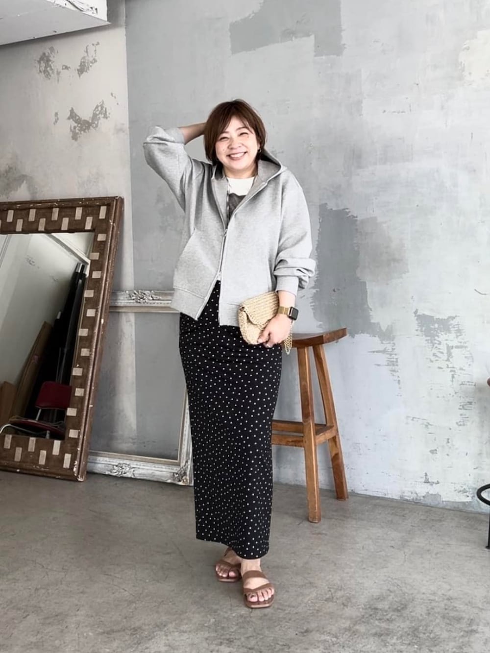 グレー系のパーカー、ブラック系のスカート、ゴールド系のショルダーバッグを着用したレディースの夏コーディネートの2枚目の写真