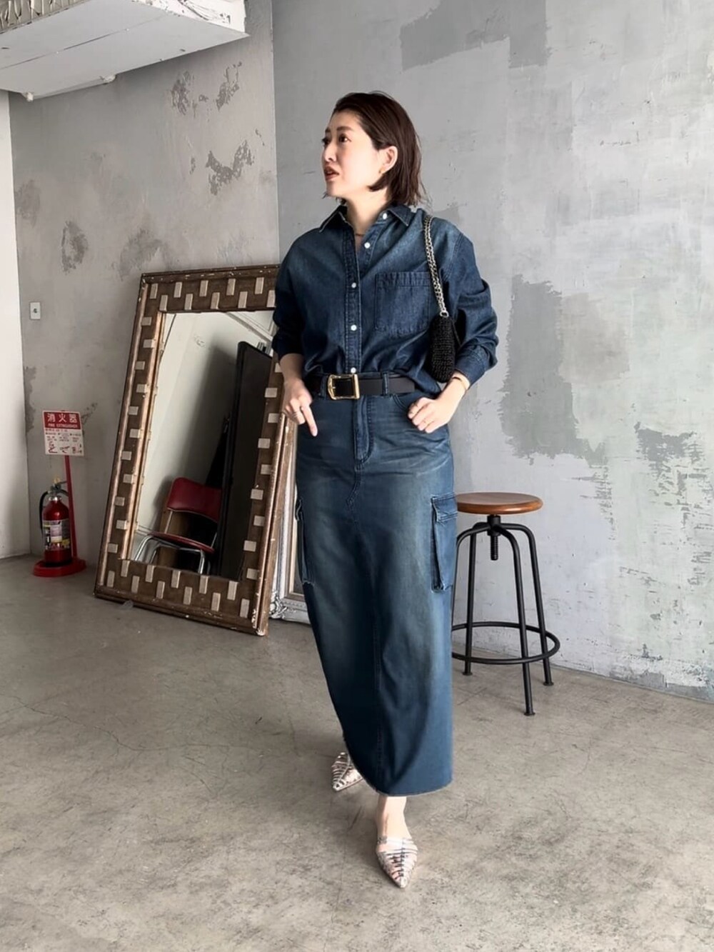 ブルー系のデニムスカート、ブラック系のショルダーバッグ、ブルー系のシャツ/ブラウスを着用したレディースの春コーディネートの2枚目の写真