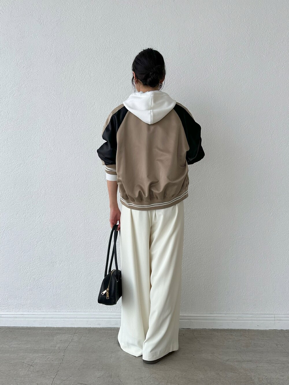 ホワイト系のスラックス、ブラック系のショルダーバッグ、ベージュ系のブルゾンを着用したレディースの夏コーディネートの3枚目の写真