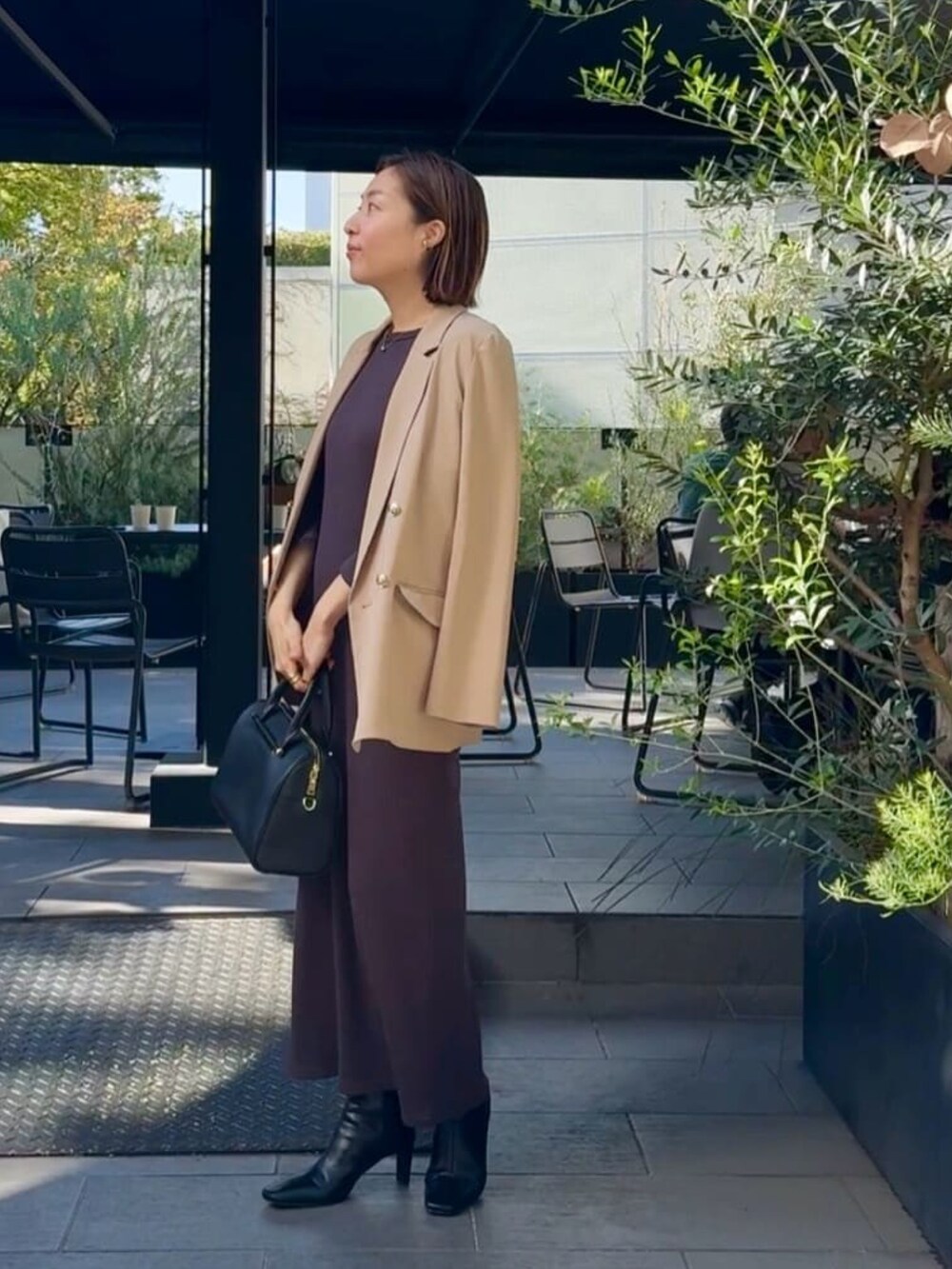 イエロー系のテーラードジャケット、ブラウン系のワンピース、ブラック系のバッグを着用したレディースの秋コーディネートの2枚目の写真