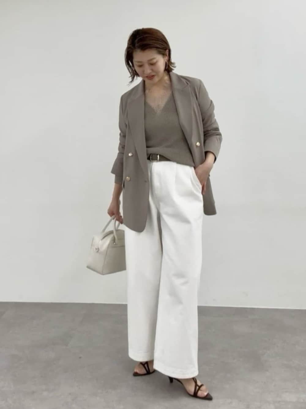 ブラウン系のテーラードジャケット、ホワイト系のデニムパンツ、ホワイト系のボストンバッグを着用したレディースの春コーディネートの2枚目の写真