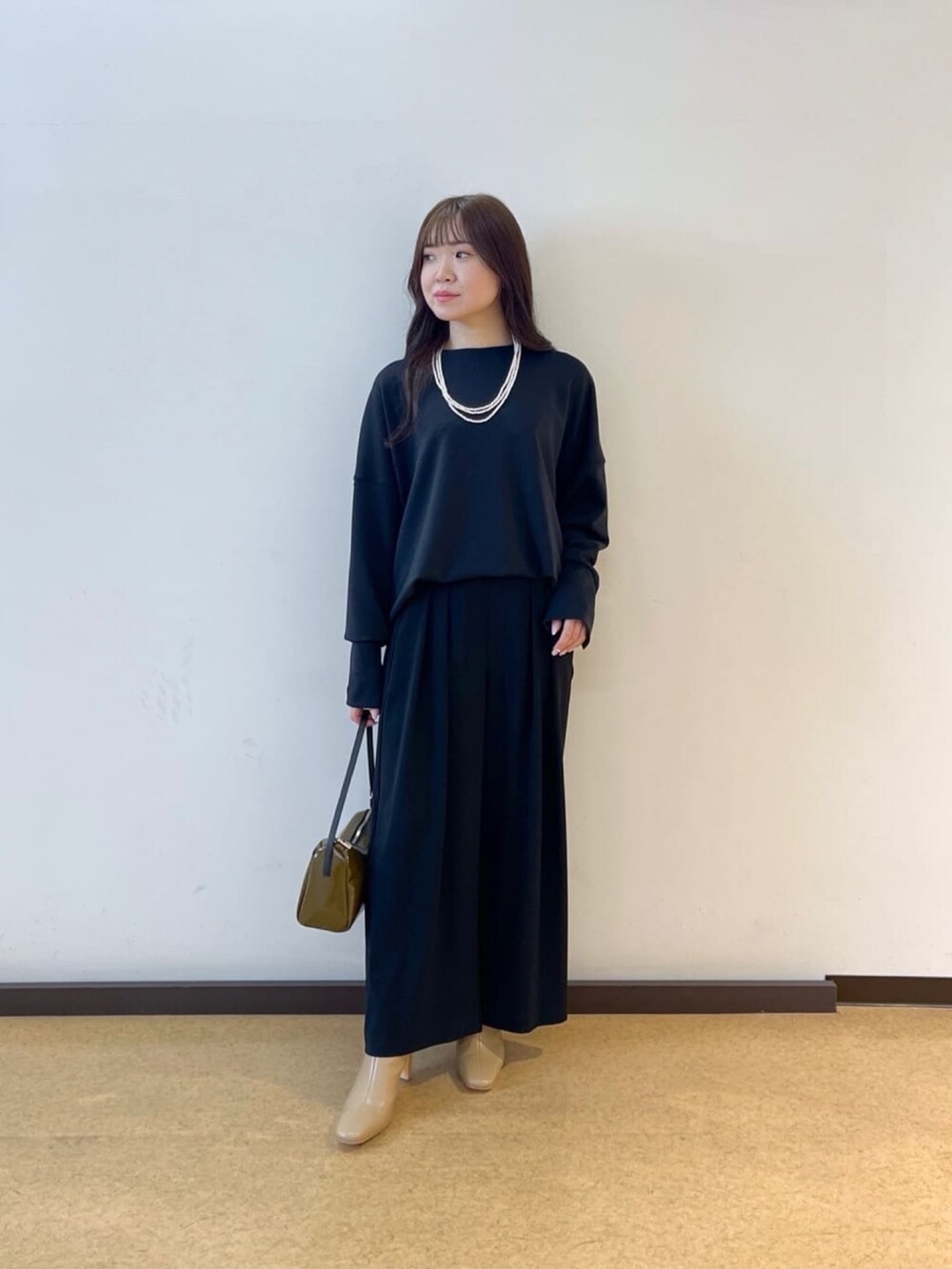 ブラック系のスラックス、ブラック系のTシャツ/カットソー、グリーン系のショルダーバッグを着用したレディースの春コーディネートの4枚目の写真