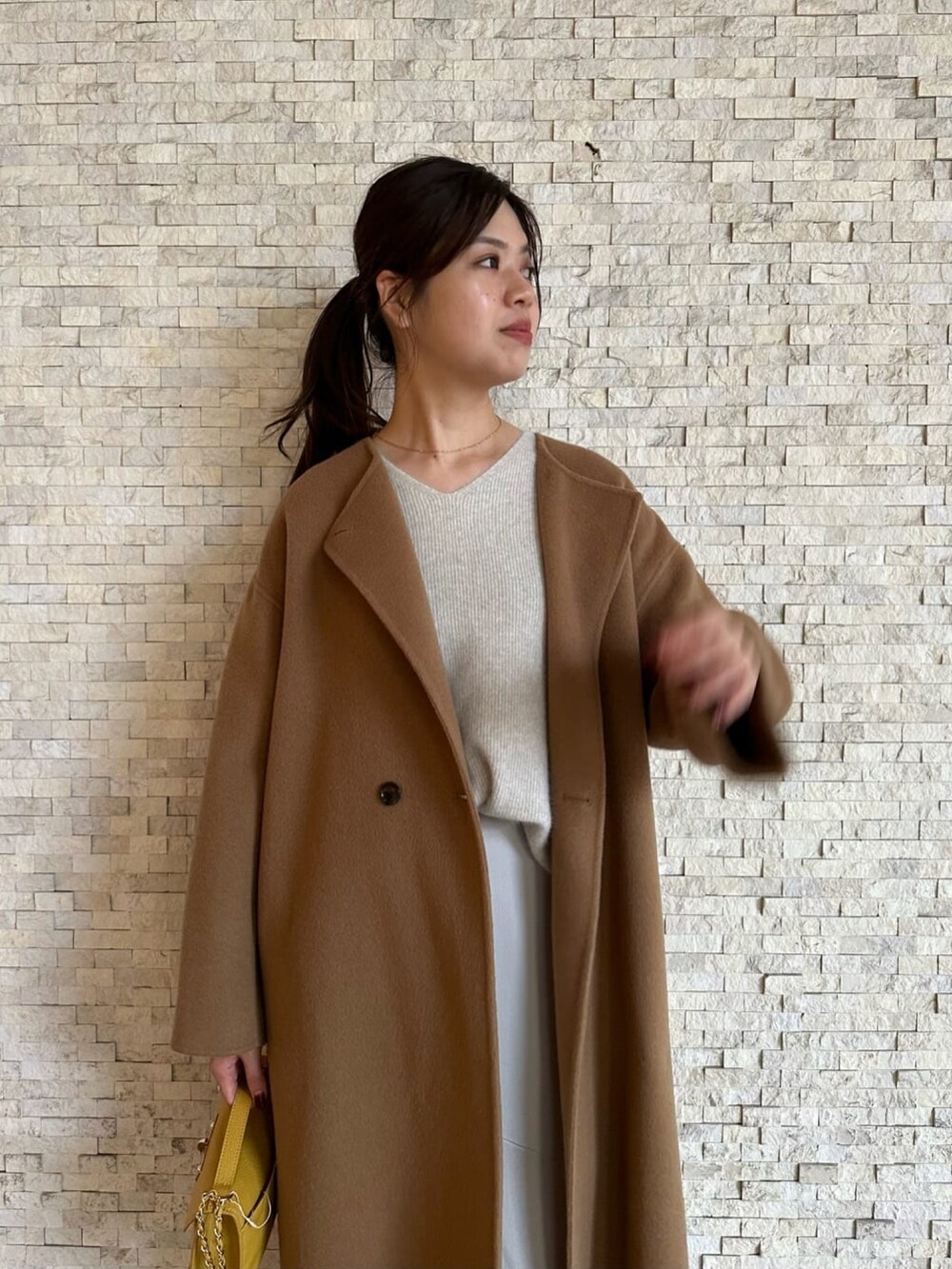 イエロー系のノーカラーコート、グレー系のニット/セーター、ブラウン系のブーツを着用したレディースの秋コーディネートの4枚目の写真