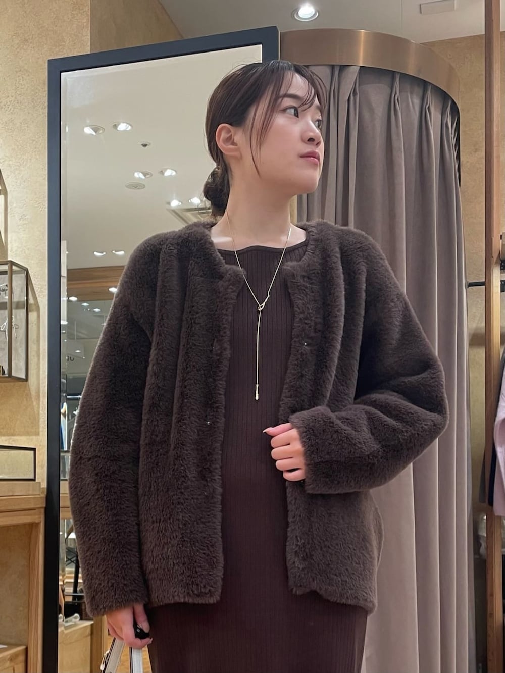 ブラウン系のカーディガン/ボレロ、ブラウン系のワンピース、ブラック系のブーツを着用したレディースの秋コーディネートの3枚目の写真