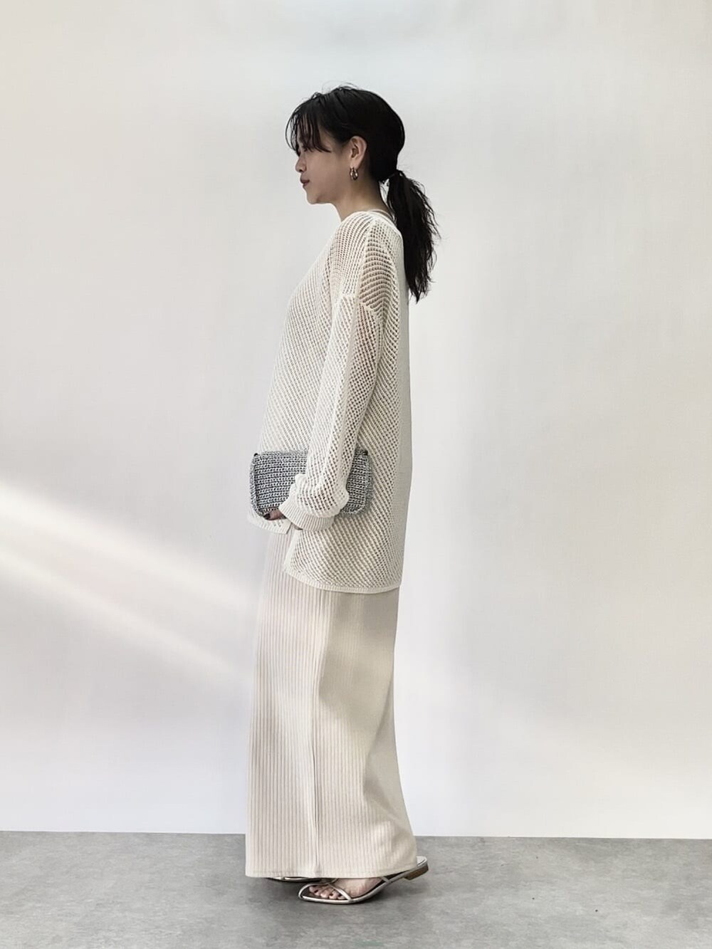 ホワイト系のワンピース、オレンジ系のニット/セーターを着用したレディースの春コーディネートの2枚目の写真