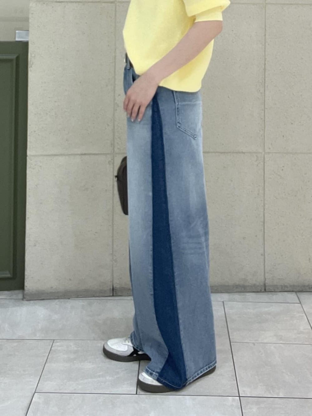 ブラウン系のボストンバッグ、イエロー系のニット/セーター、ブルー系のデニムパンツを着用したレディースの春コーディネートの8枚目の写真