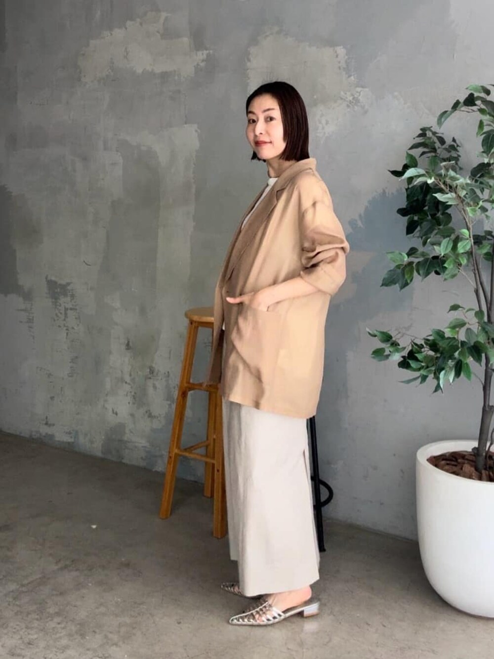 ブラック系のテーラードジャケット、ホワイト系のニット/セーター、ベージュ系のスカートを着用したレディースの春コーディネートの2枚目の写真