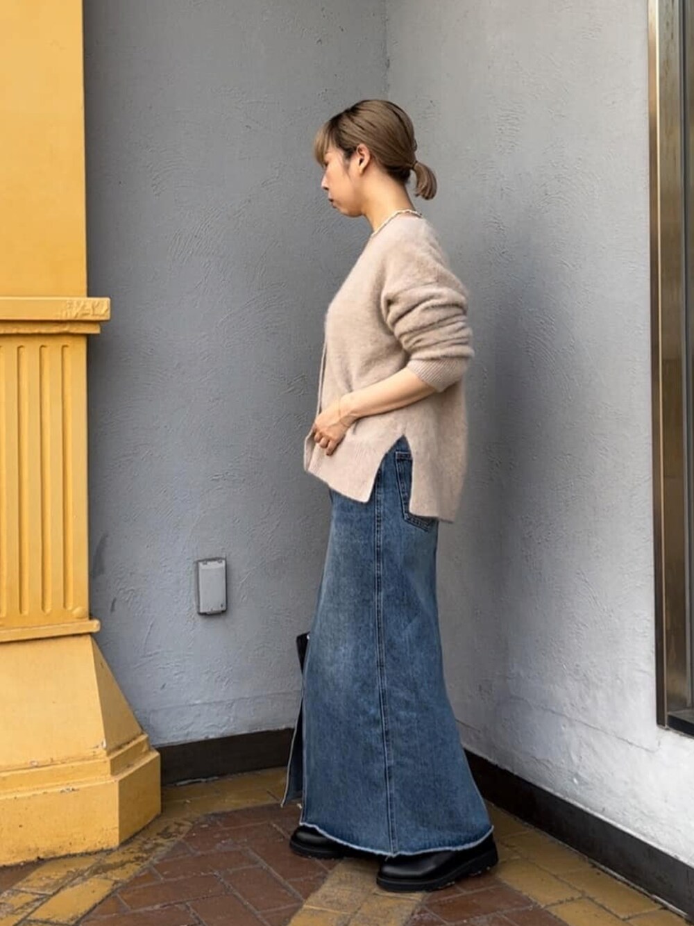 グレー系のカーディガン/ボレロ、ブルー系のデニムスカート、ブラック系のショルダーバッグを着用したレディースの冬コーディネートの2枚目の写真